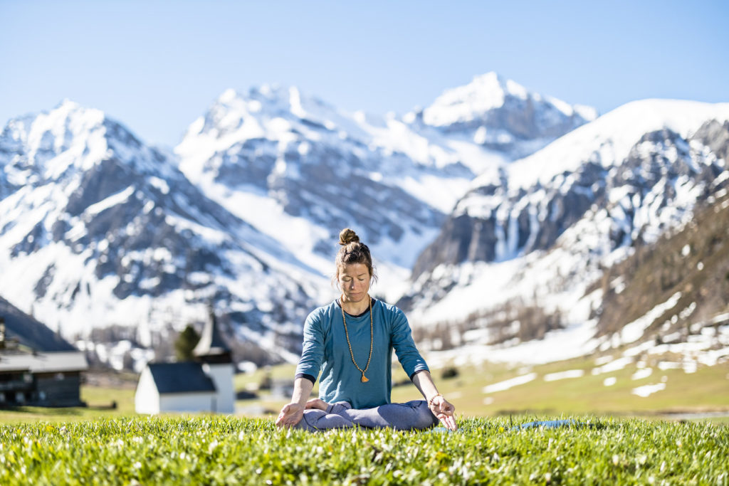 Frau geniesst die Ruhe mit Yoga in der herrlichen Bergwelt von Davos.