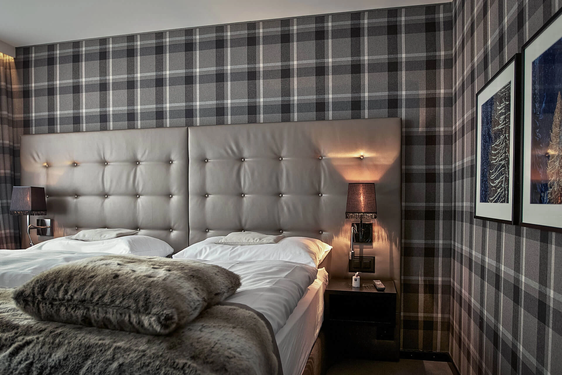 Schlafbereich der Alpine Signature Suite mit karierter Wand und Fellplaid