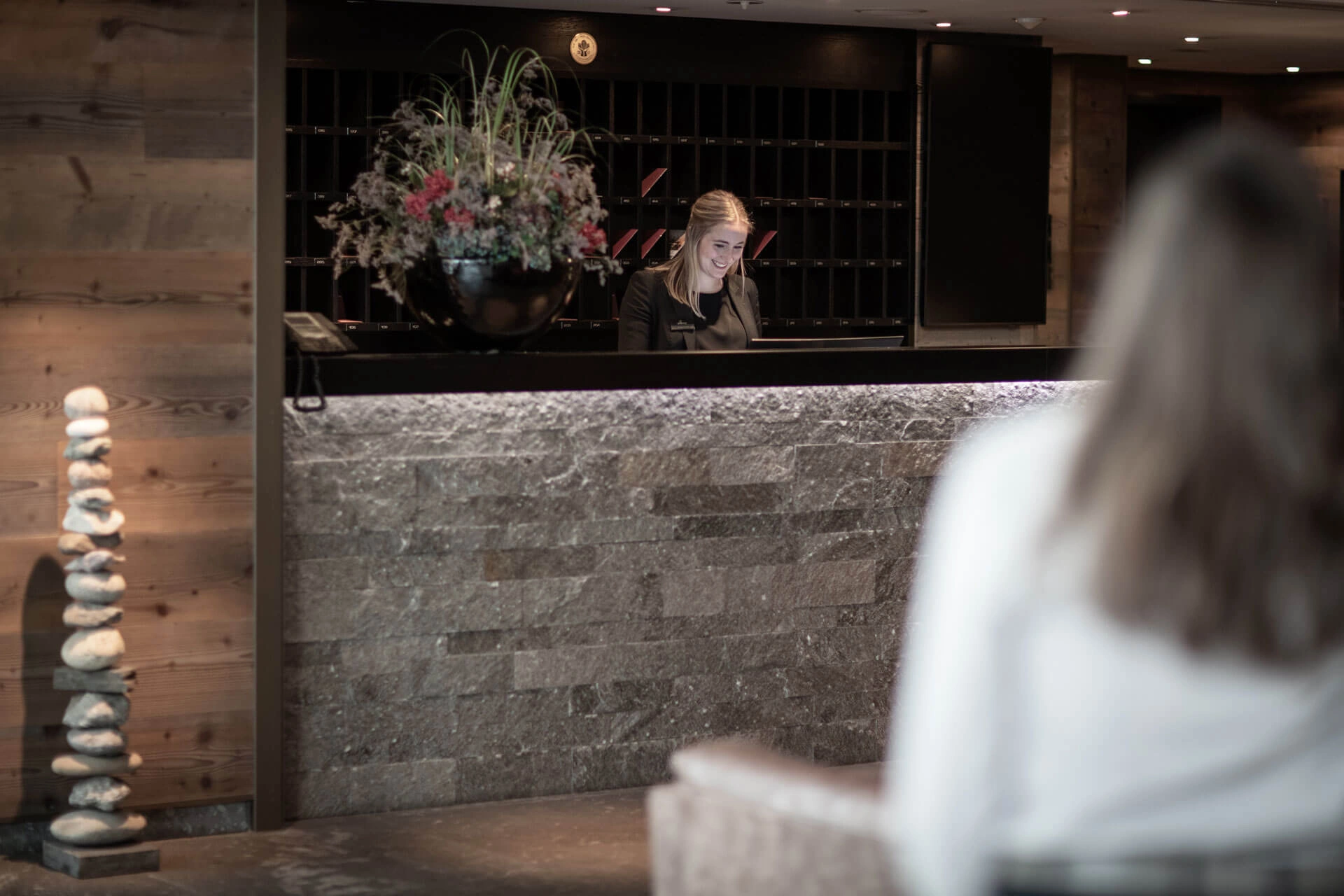 Mitarbeiterin an der Rezeption des Hotel Grischa hinter einer Natursteintheke