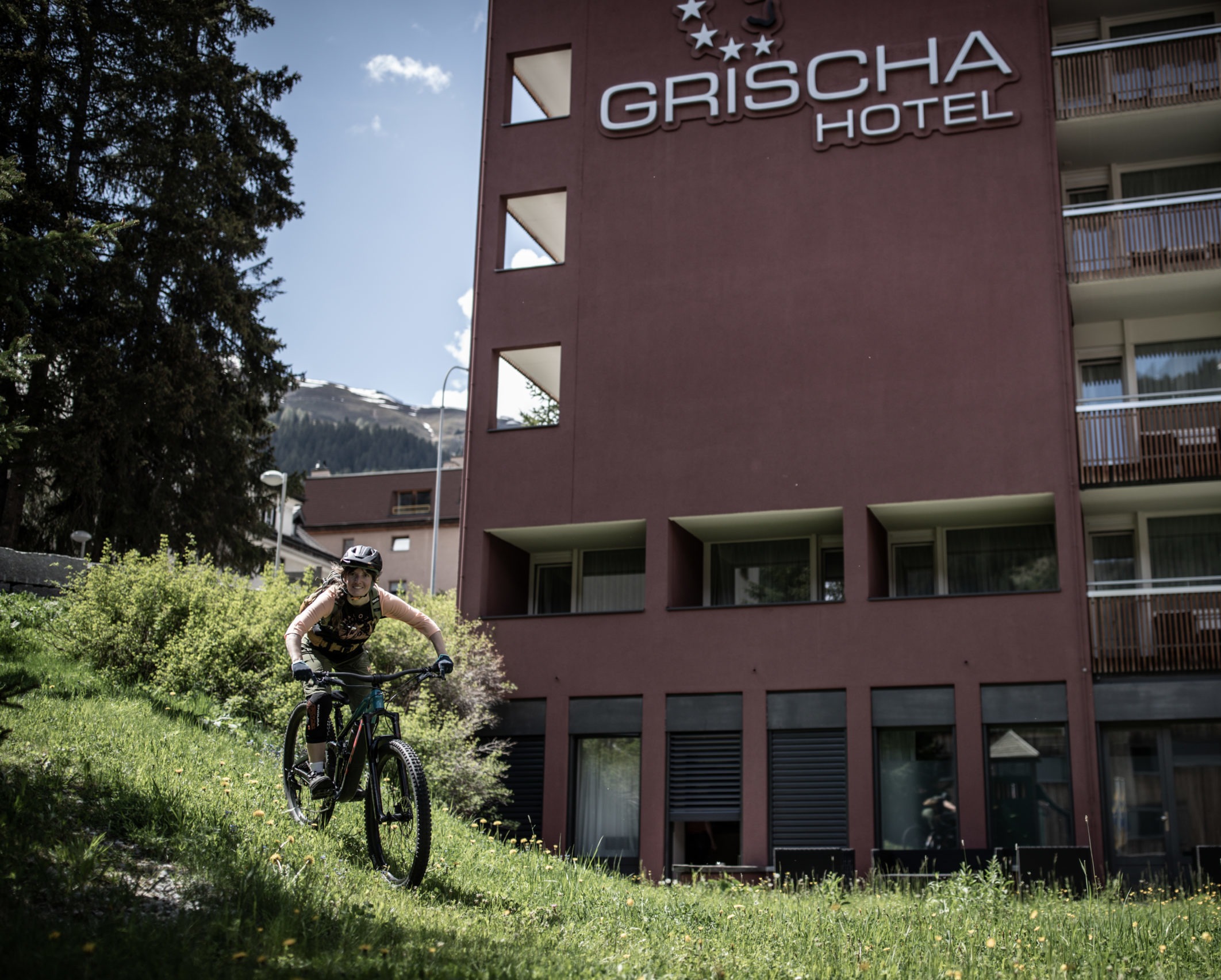 Mountain biker riding across the meadow in front of Hotel Grischa in Davos