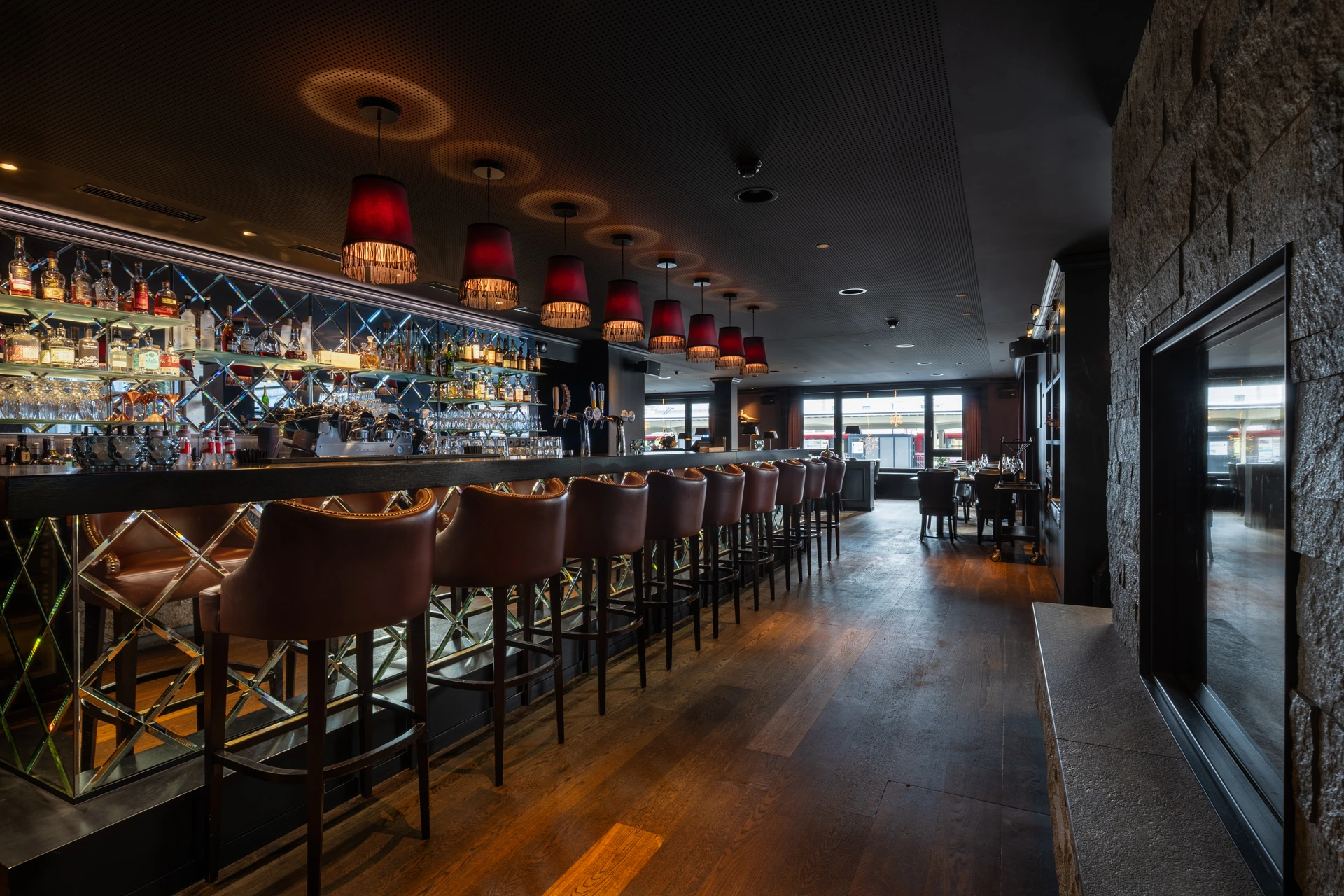 Elegante Hotelbar mit stilvollen Barhockern, beleuchteten Spirituosenregalen und gemütlichem Ambiente im Hotel Grischa in Davos.