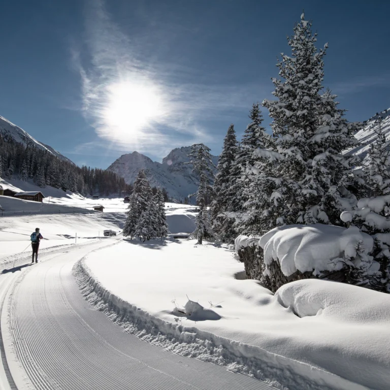 Cross-country skiers on the freshly groomed trail in the snowy valley near Davos