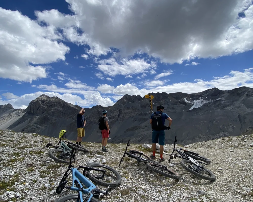 Drei Biker legen eine Pause auf einem Steinfeld hoch über Davos ein