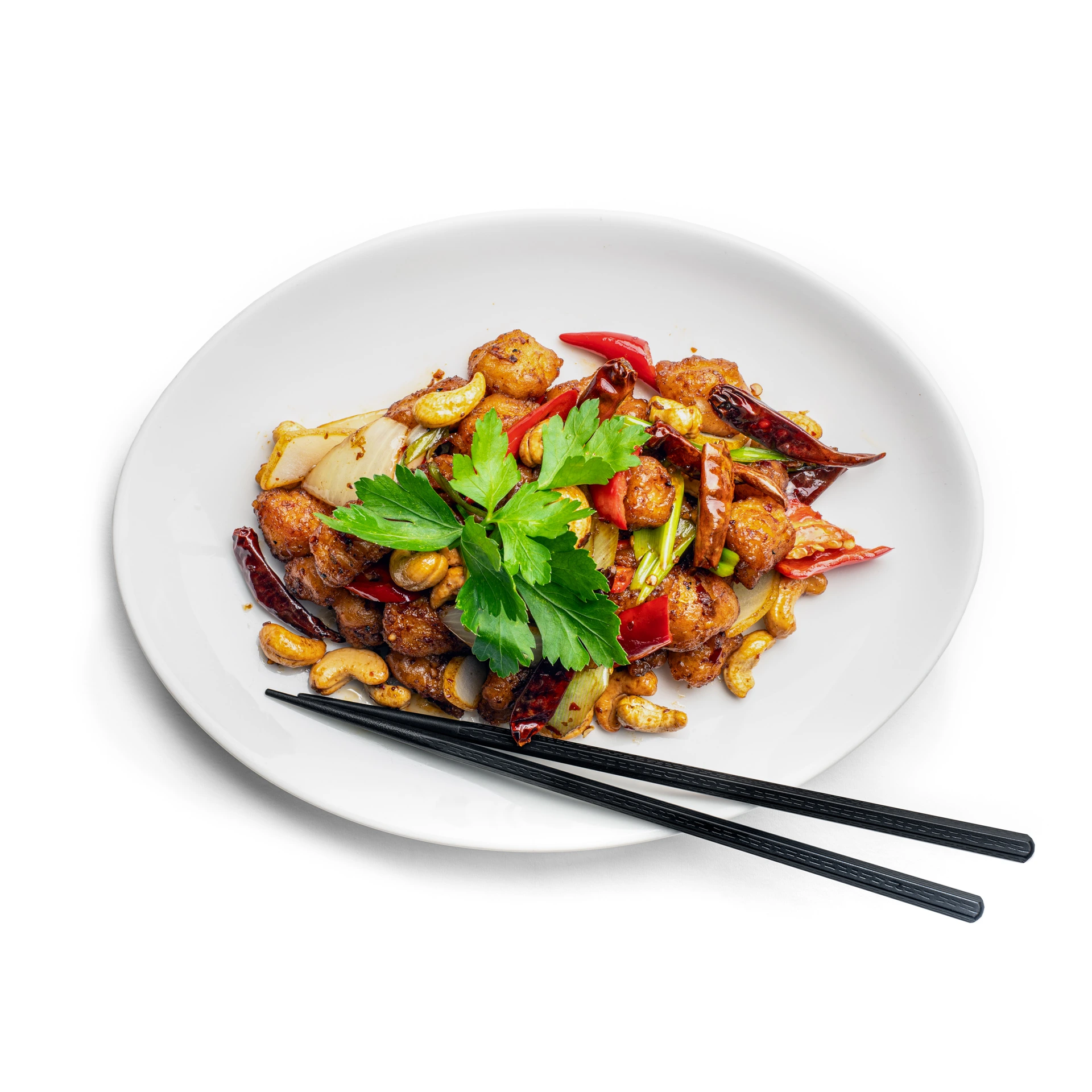 Wok-Gericht mit Cashewnüssen, Chili und Koriander auf weissem Teller mit Essstäbchen