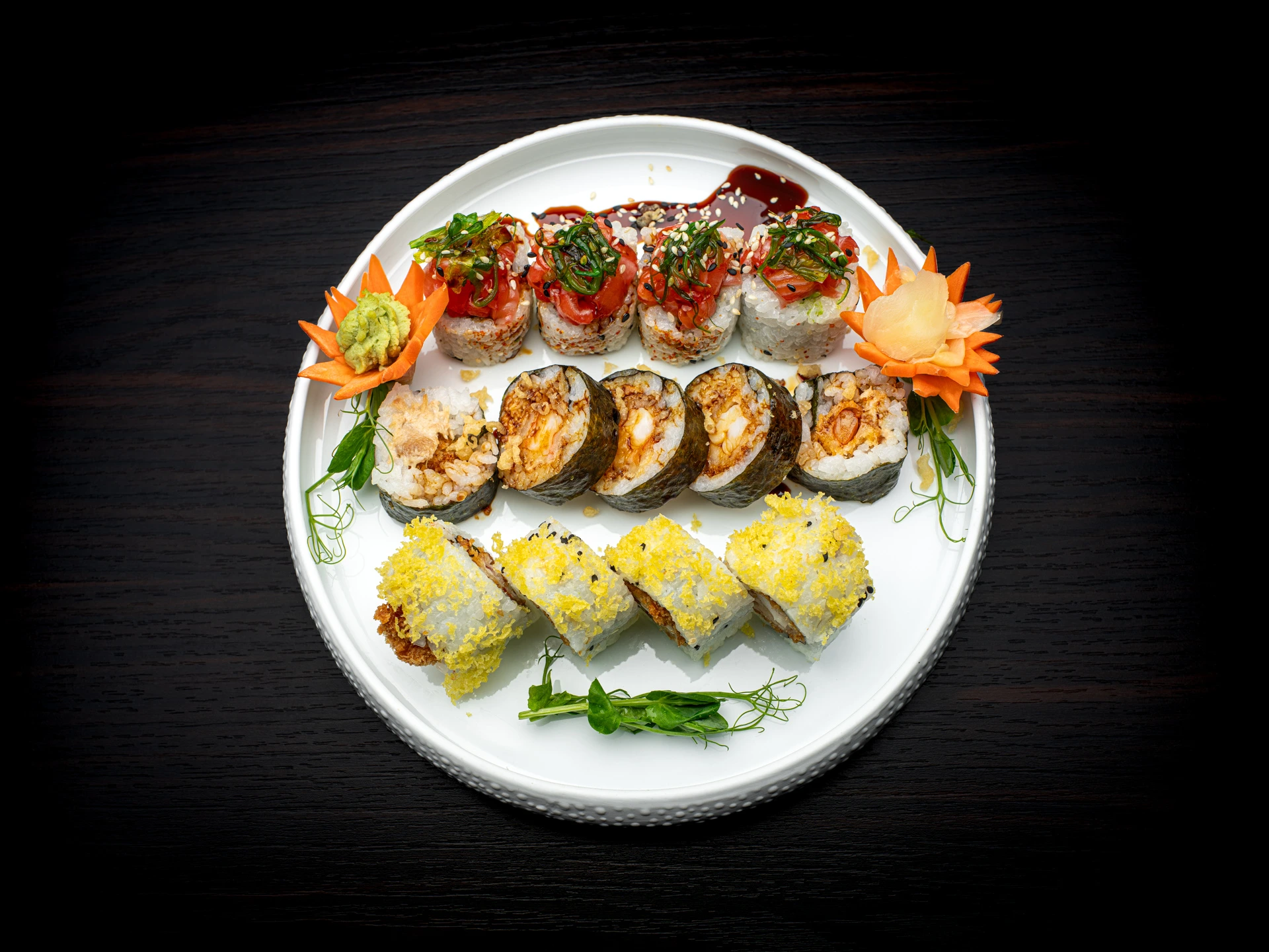 Köstliche Sushis in verschiedenen Farben mit zwei Dekorationsblumen aus Karotten.