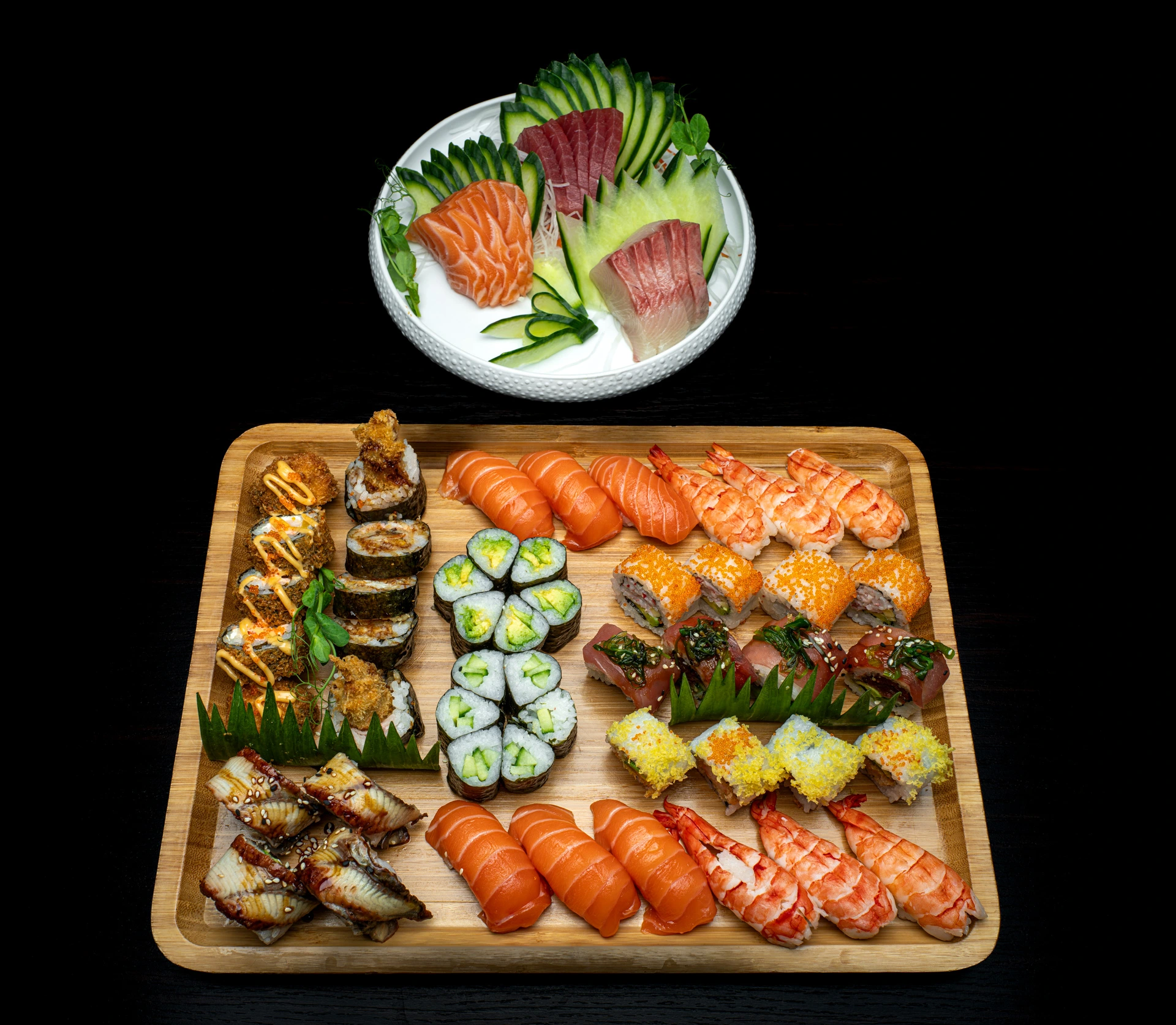 Großzügige Sushi- und Sashimi-Platte mit Lachs, Thunfisch, Crevetten, Maki, Nigiri und verschiedenen Spezialrollen auf einem Holzbrett.