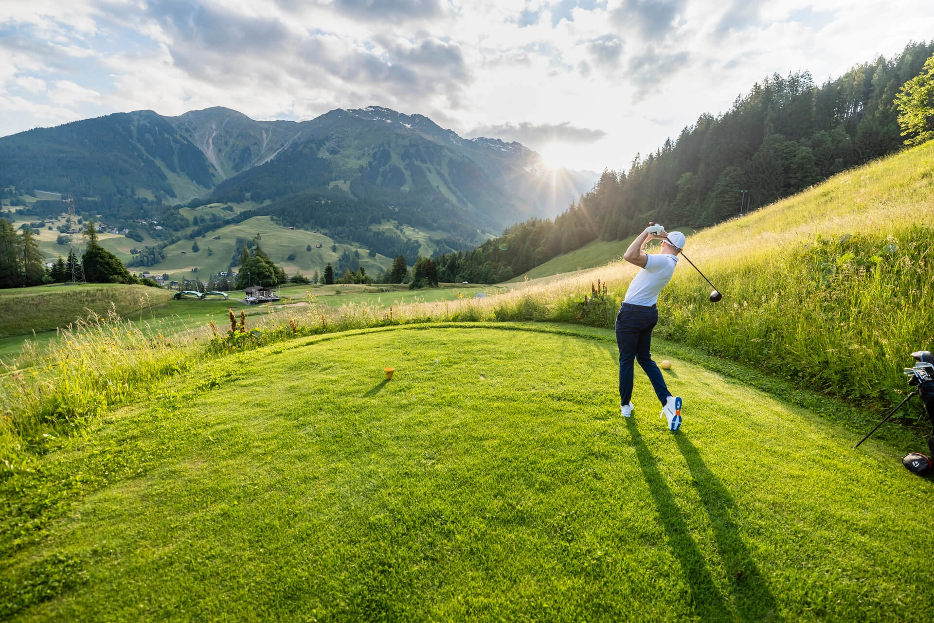 Golferin schlägt auf dem Golfplatz Klosters im Abendlicht ab