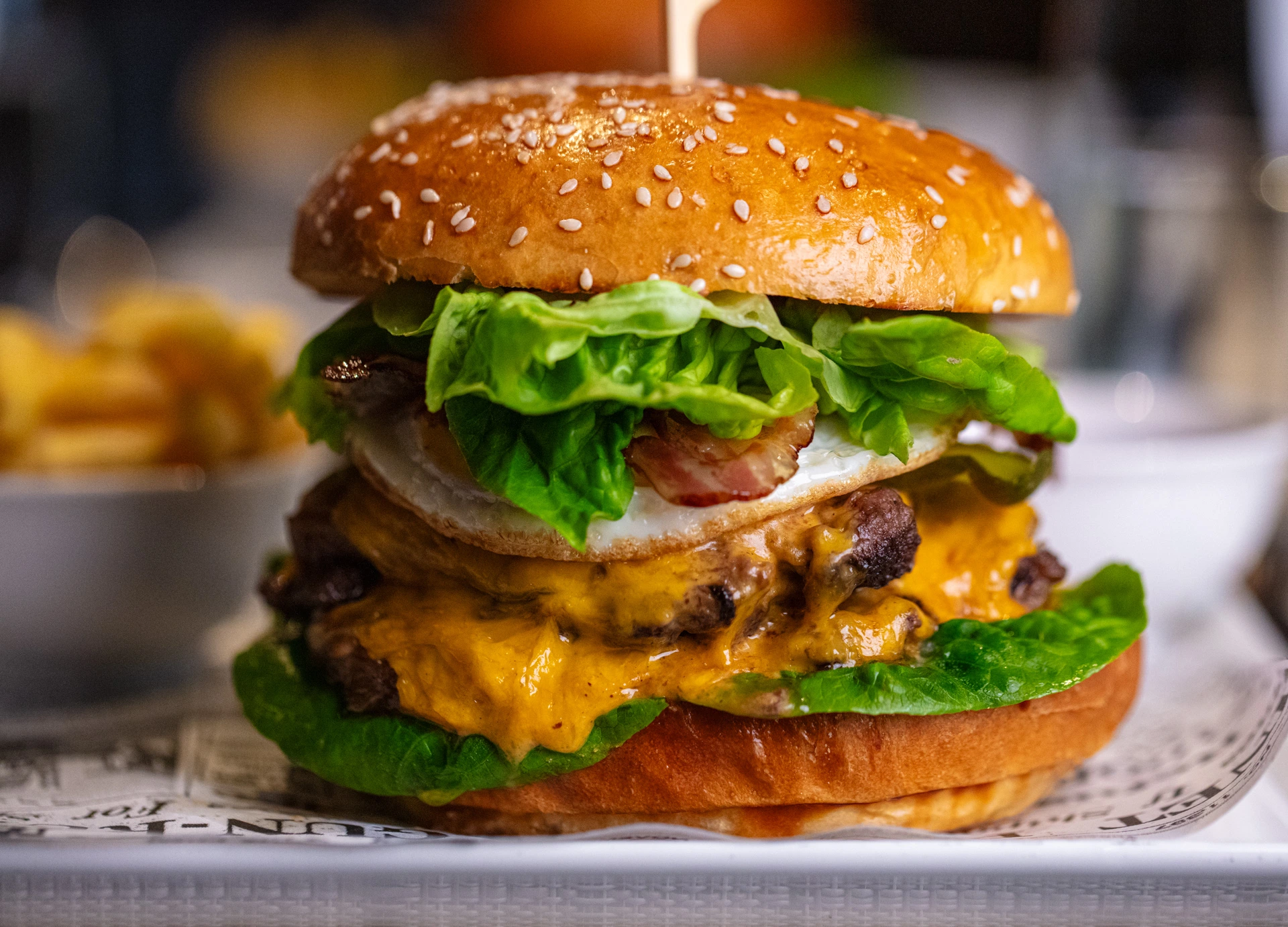 Saftiger Cheeseburger mit doppelt Rindfleisch, Cheddar, Speck, Spiegelei und frischem Salat, serviert mit Pommes frites im Restaurant Pulsa.