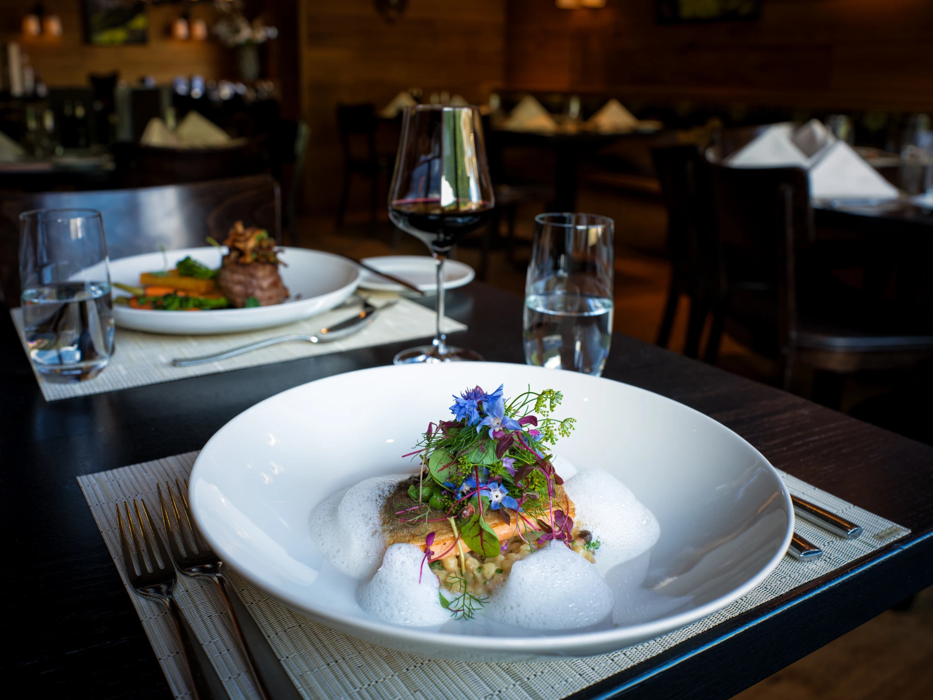 Gebratenes Saiblingsfilet auf cremigem Risotto, verfeinert mit Wildkräutern, essbaren Blüten und feinem Schaum im Restaurant Pulsa.