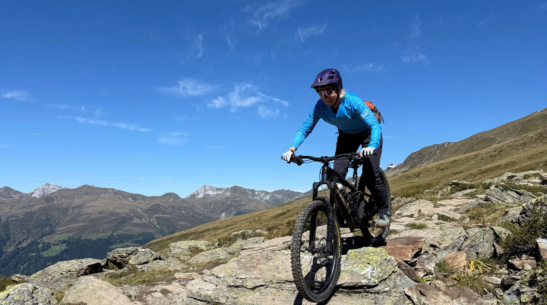 Mountainbikerin fährt über einen steinigen Trail hoch über Davos