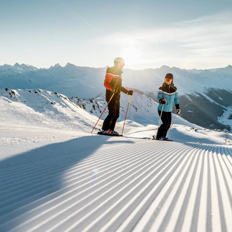 Two skiers on the freshly groomed slope in the Parsenn ski area