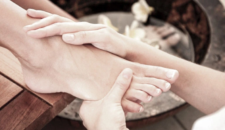 Fussmassage über einer Schale mit Blüten