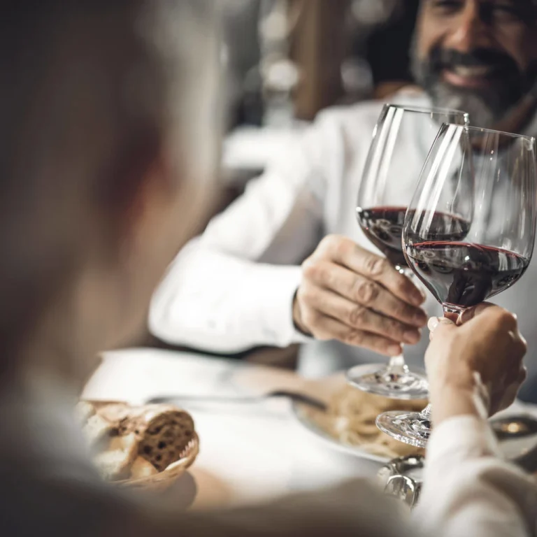 Guests clinking red wine glasses at a table