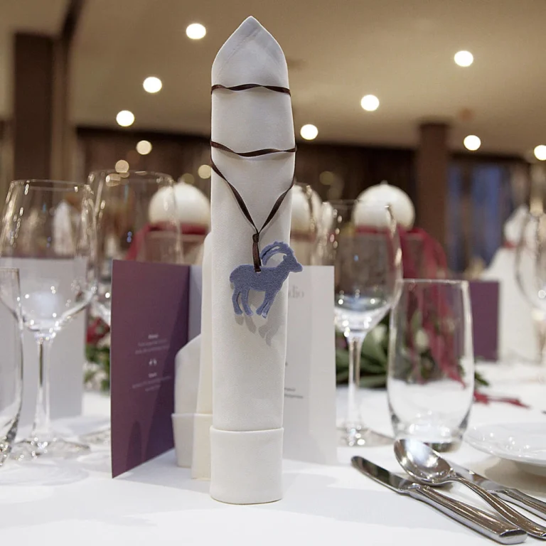 Napkin with ibex pendant and menu card on a festively set table