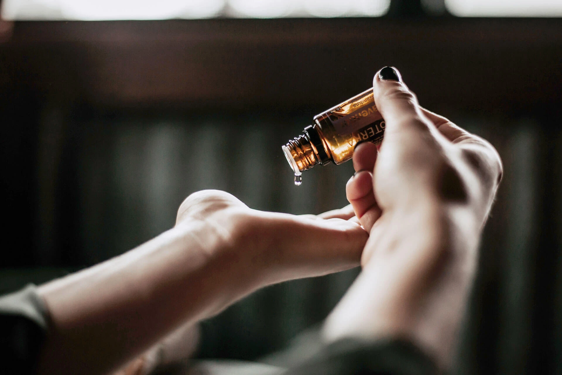 Massageöl wird aus einem Fläschchen auf die Hand getropft