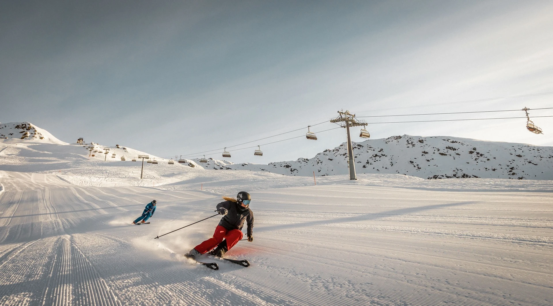 Zwei Skifahrer auf der Piste unter dem Sessellift im Skigebiet Madrisa