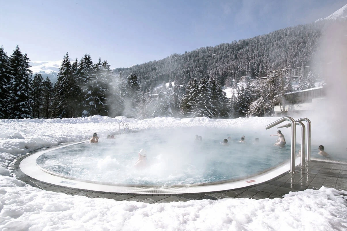 Gäste im dampfenden Aussenwhirlpool im Schnee