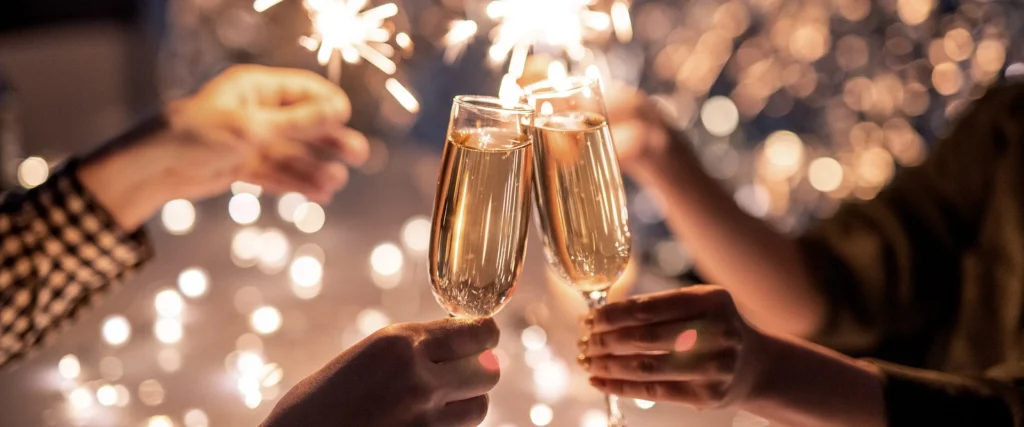 Zwei Personen stossen mit Champagnergläsern vor Wunderkerzen an