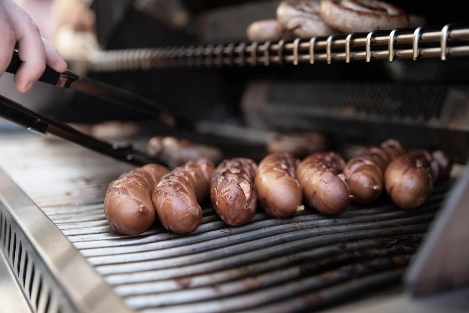 Bratwürste werden auf dem Grill gewendet