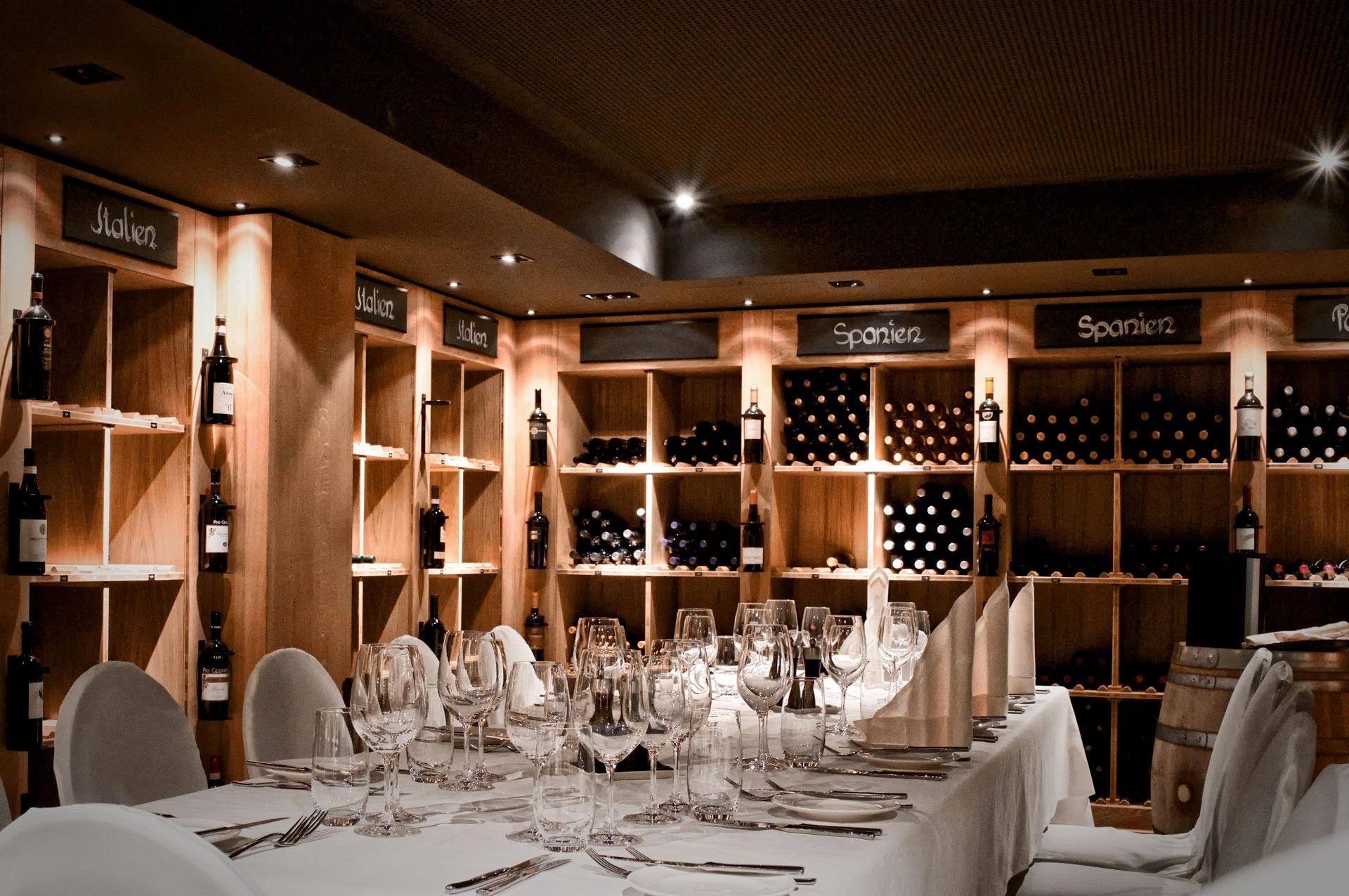 Gedeckte Tafel im Weinkeller vor den beleuchteten Weinregalen