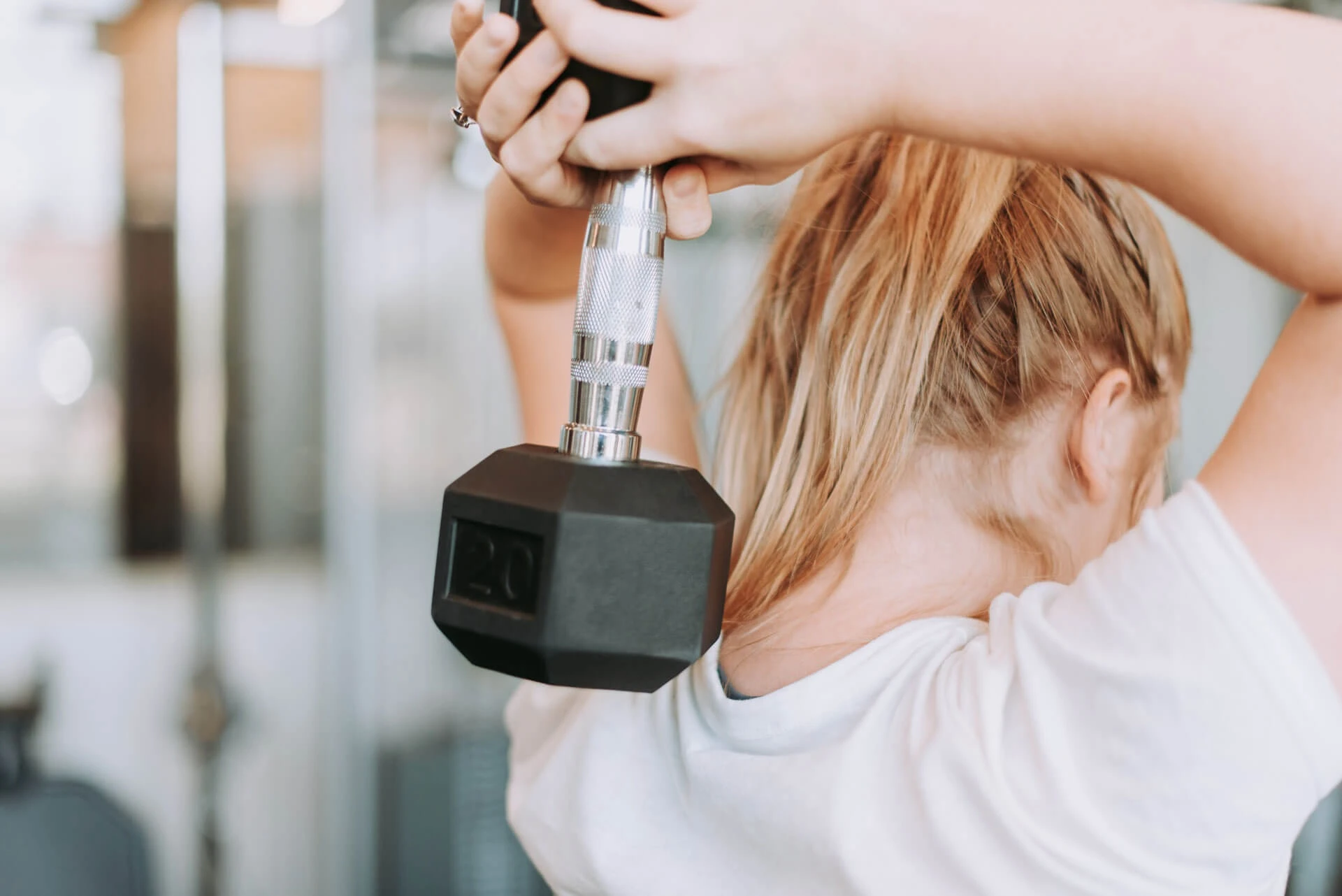 Frau trainiert im Fitnessraum mit einer Kurzhantel