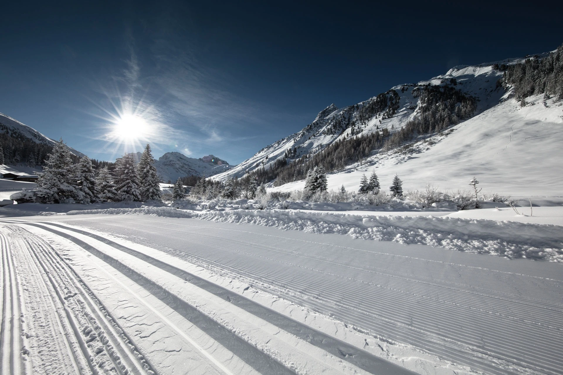 Frisch gespurte Langlaufloipe im verschneiten Tal bei Sonnenschein