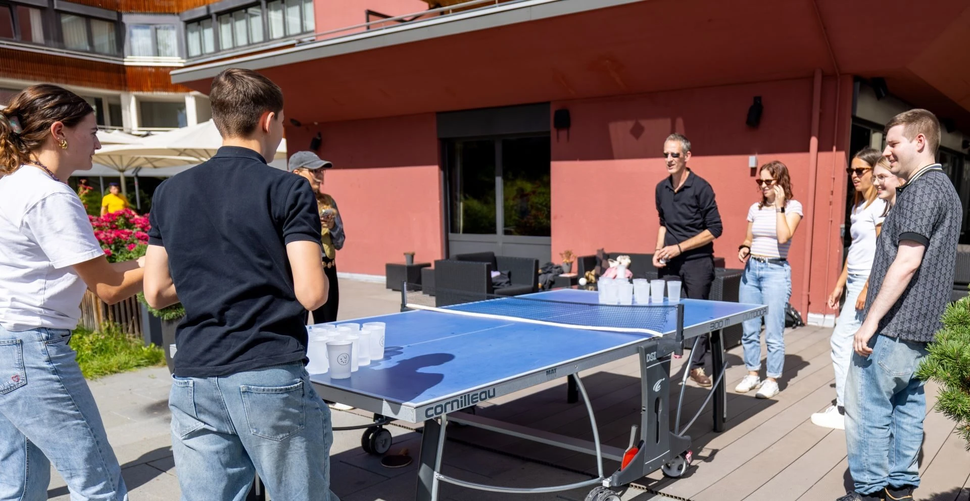Gäste spielen Beerpong am Tischtennistisch auf der Terrasse