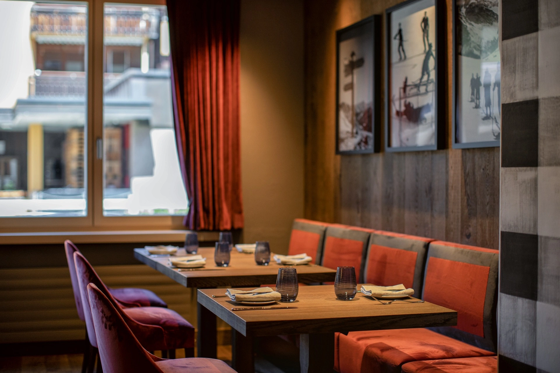 Gemütliche Sitzecke im Restaurant mit roten Polsterbänken, gedeckten Holztischen und stimmungsvoller Beleuchtung.