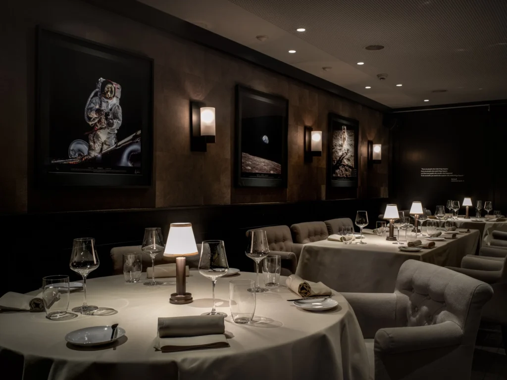 Gedeckte Tische im Gourmetrestaurant Apollo vor den beleuchteten Astronautenbildern