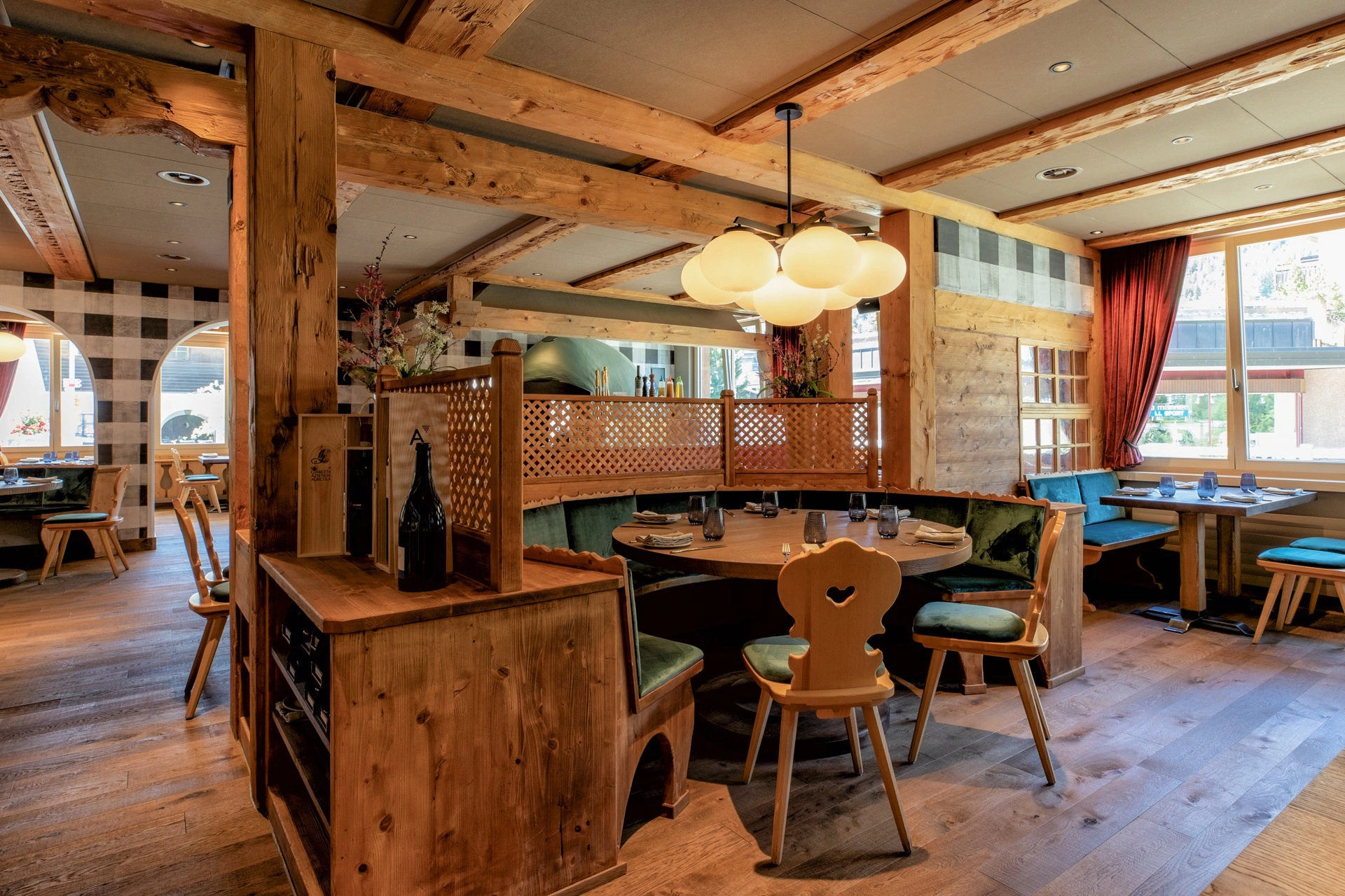 Gemütlicher Restaurantbereich mit warmen Holzelementen, runden Sitznischen und stilvoll eingedeckten Tischen.