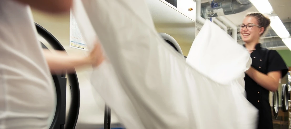 Employees folding bed linen in the hotel laundry