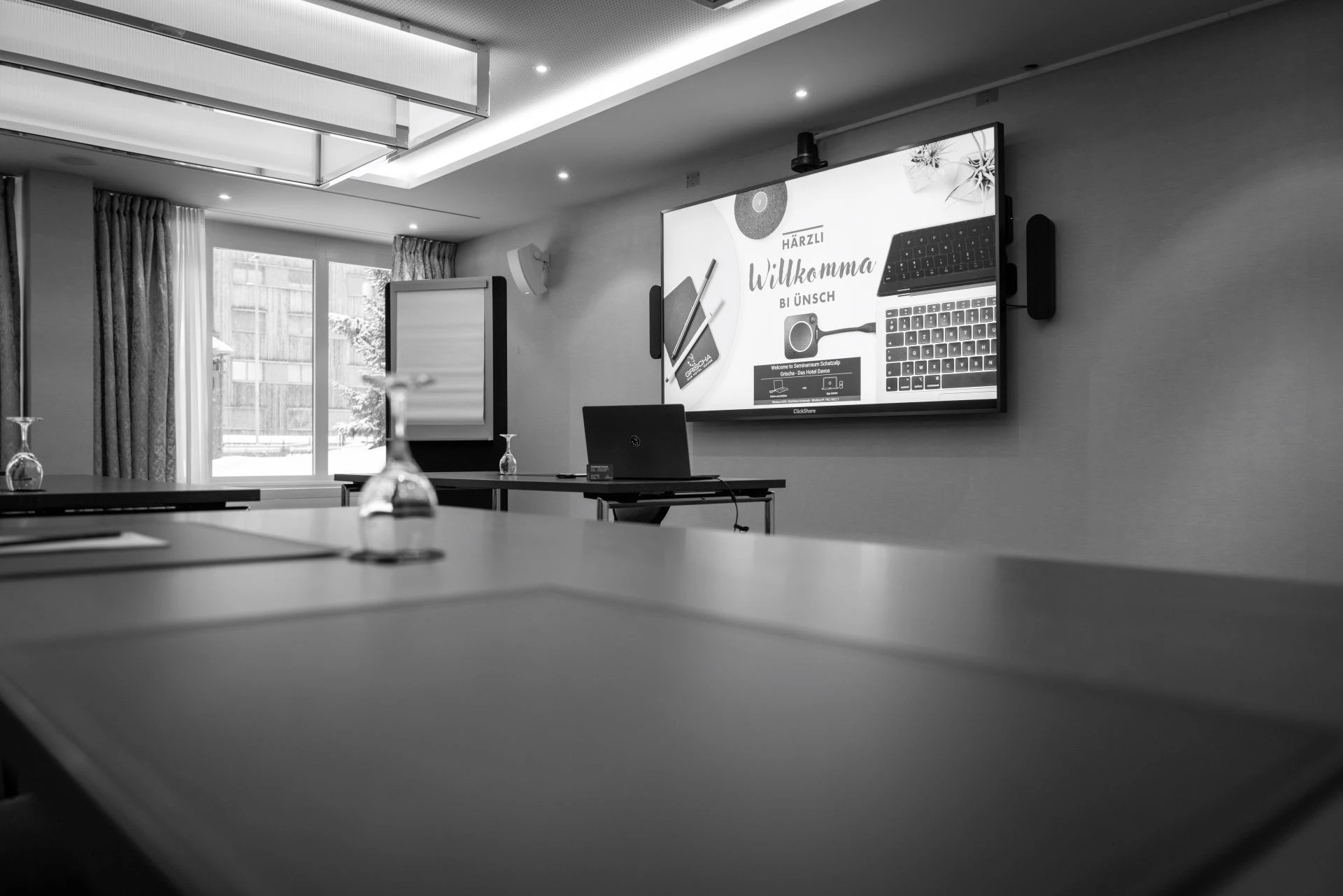 Seminarraum mit Bildschirm, Flipchart und langem Konferenztisch in Schwarz-Weiss