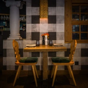 Zweiertisch mit Holzstühlen vor karierter Wand im Restaurant Bräma