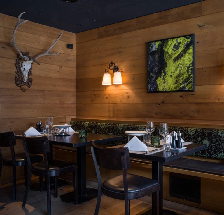 Restaurant mit Holzwänden, Hirschgeweih und beleuchtetem Wandbild
